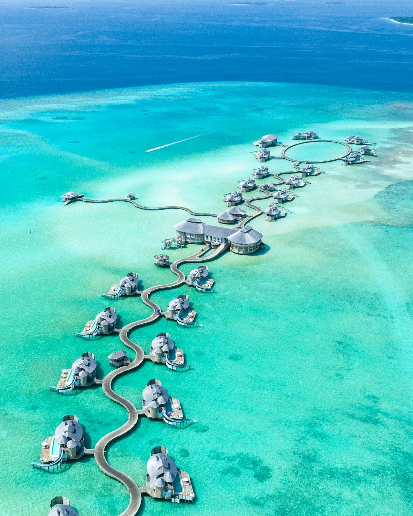 Overwater villas arranged above a clear turquoise lagoon
