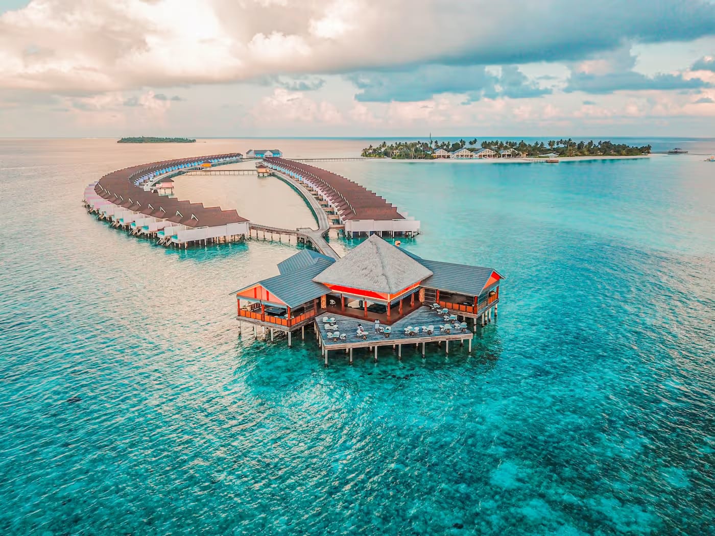 Overwater villas arranged above a clear turquoise lagoon